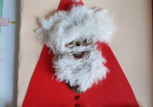 Praca plastyczna z Mikołajem w czerwonym ubraniu i puszkami z futerka.